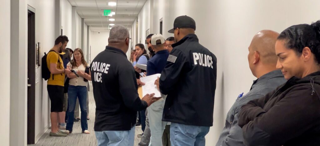 Varios agentes de Inmigración y Control de Aduanas (ICE) se encuentran en el pasillo del tribunal de inmigración de San Diego, esperando detener a las personas cuando salen de sus audiencias judiciales el jueves 22 de mayo de 2025.